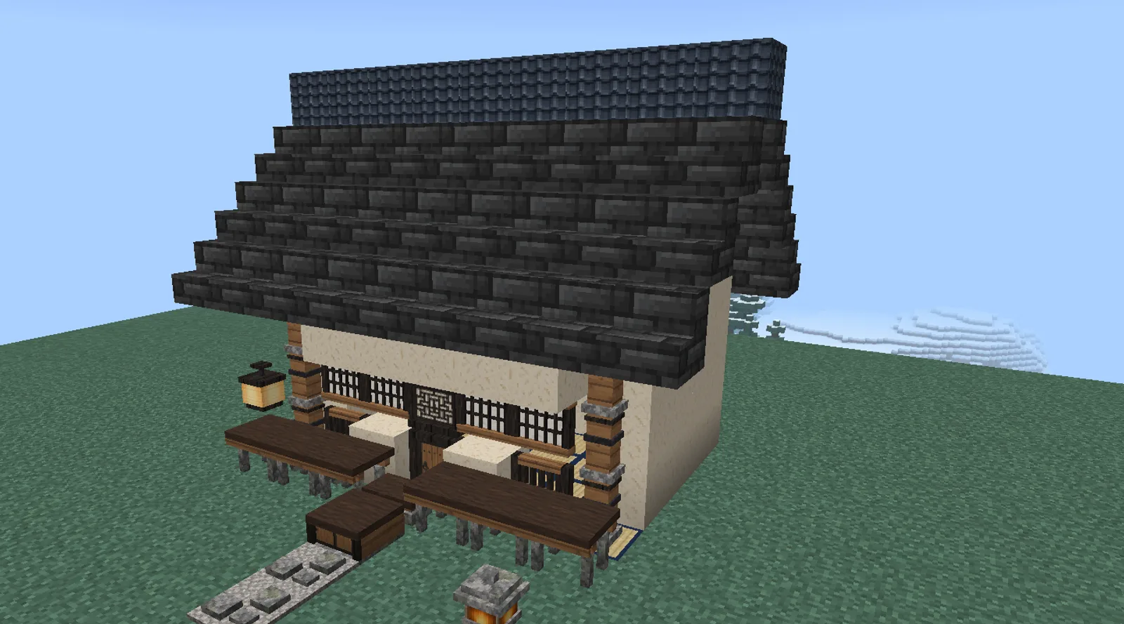 A Minecraft Japanese house with plaster walls between cedar posts, paper lattice windows, a tiled roof, a cedar veranda and a stone garden lantern